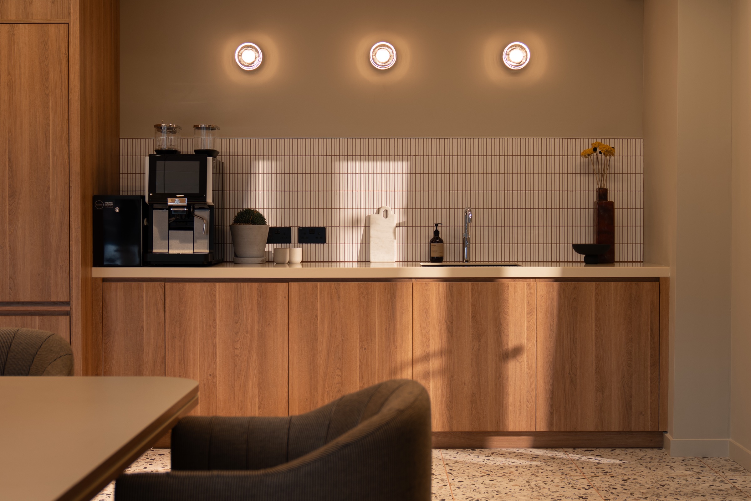 Kitchenette with tiled splashback, coffee machine and round wall lights