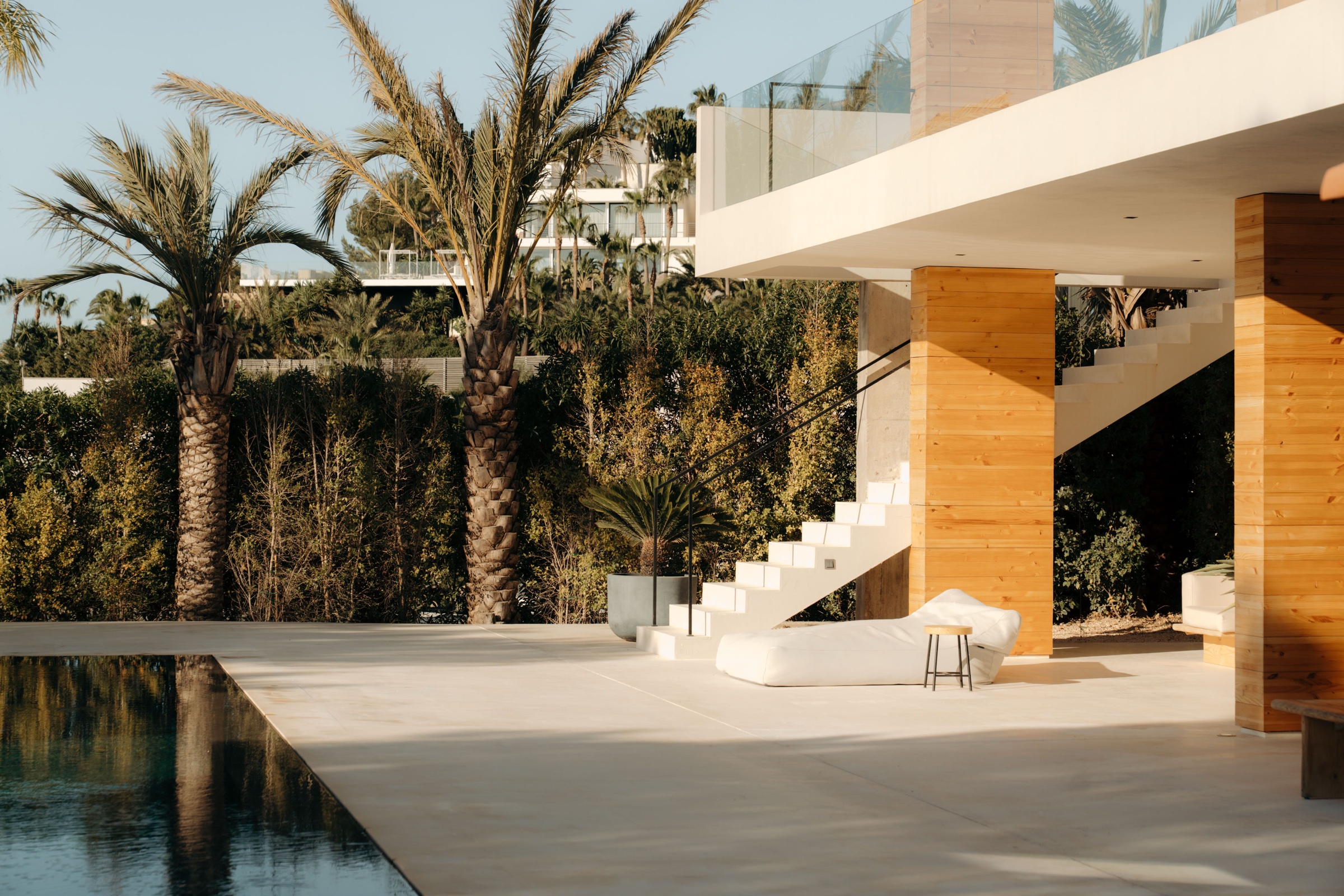 Villa poolside terrace with palm trees, a floating staircase and a sun lounger